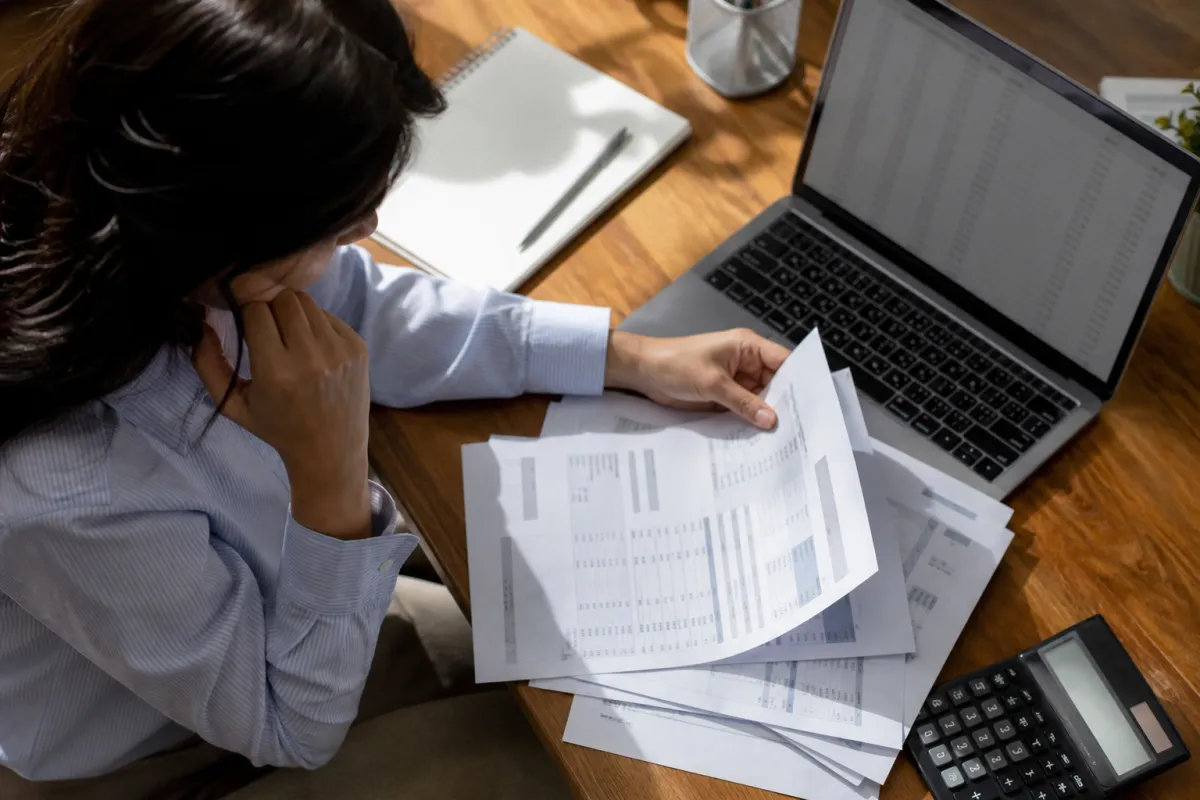 A person reviewing credit card statements and calculations in an office setting.